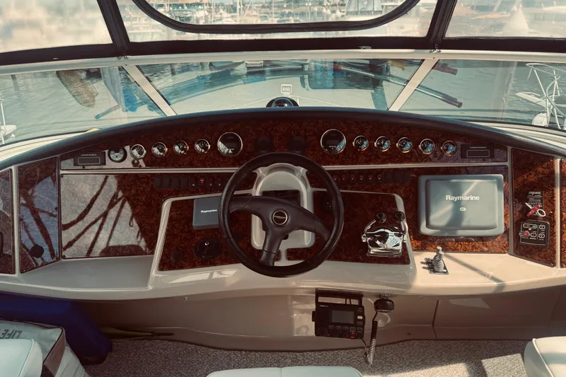Slide: The Image of 2005 Carver 466 Motor Yacht helm with steering wheel, gauges, and Raymarine navigation system. - 10