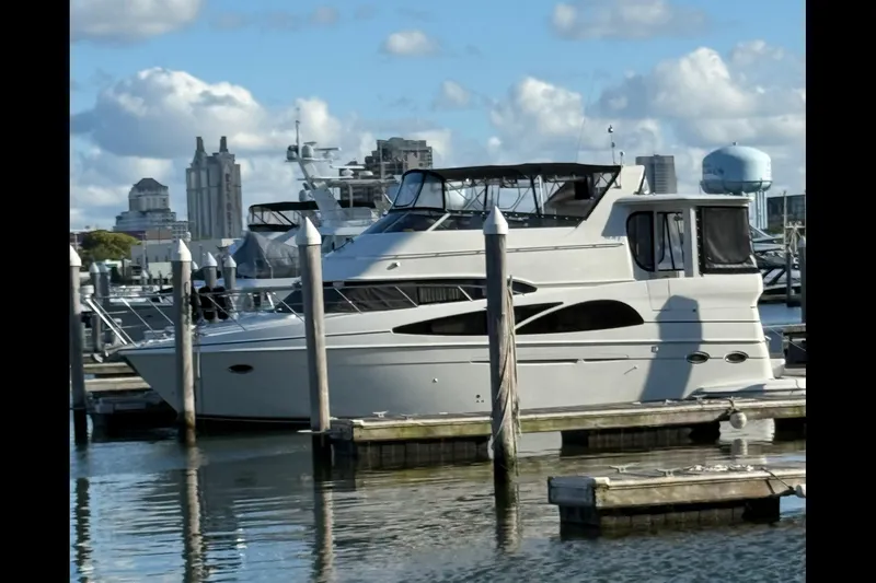 Slide: The Image of 2005 Carver 466 Motor Yacht docked in a marina, city skyline in background. - 2