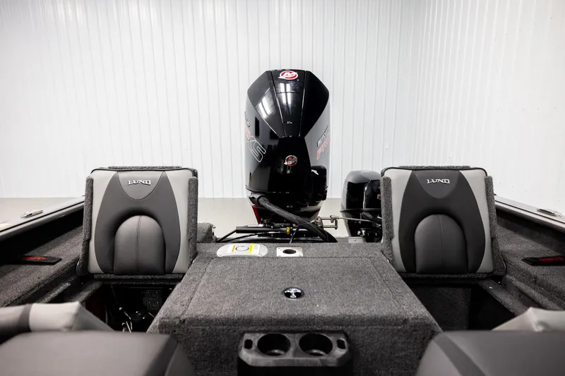 Slide: The Image of 2026 Lund 2075 Impact XS boat interior with motor and seating in a showroom. - 19