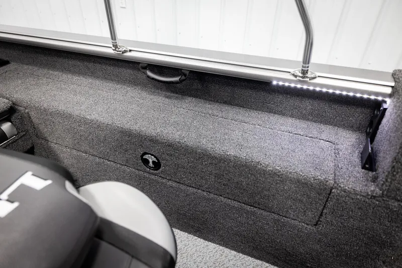 Slide: The Image of 2026 Lund 2075 Impact XS boat interior with LED lighting and carpeted storage area. - 29