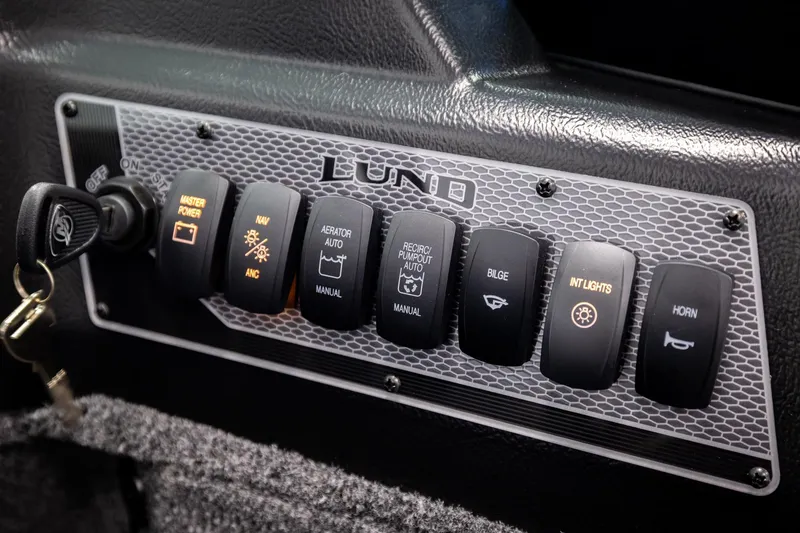 Slide: The Image of Control panel of 2026 Lund 2075 Impact XS boat with various switches and key ignition. - 38