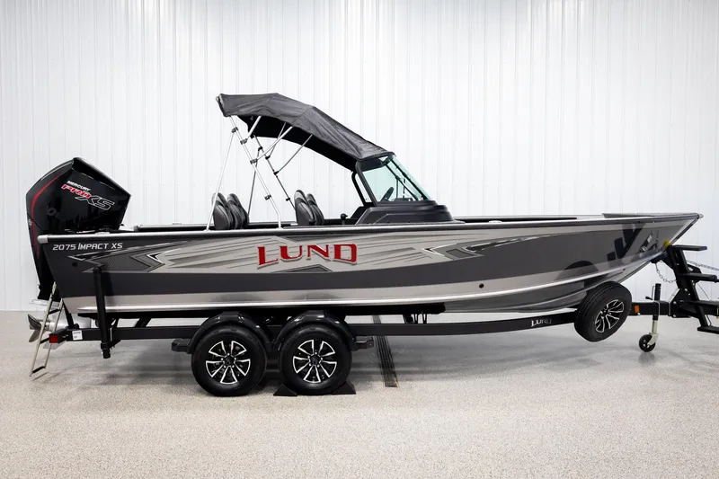 Slide: The Image of 2026 Lund 2075 Impact XS boat with canopy on trailer in showroom. - 4