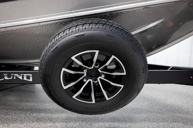 Slide: The Image of 2026 Lund 2075 Impact XS boat trailer wheel, black alloy rim, close-up view. - 57