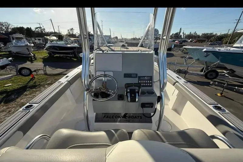 Slide: The Image of 2023 Falcon Boats F22 cockpit with steering wheel and controls, parked among other boats. - 28