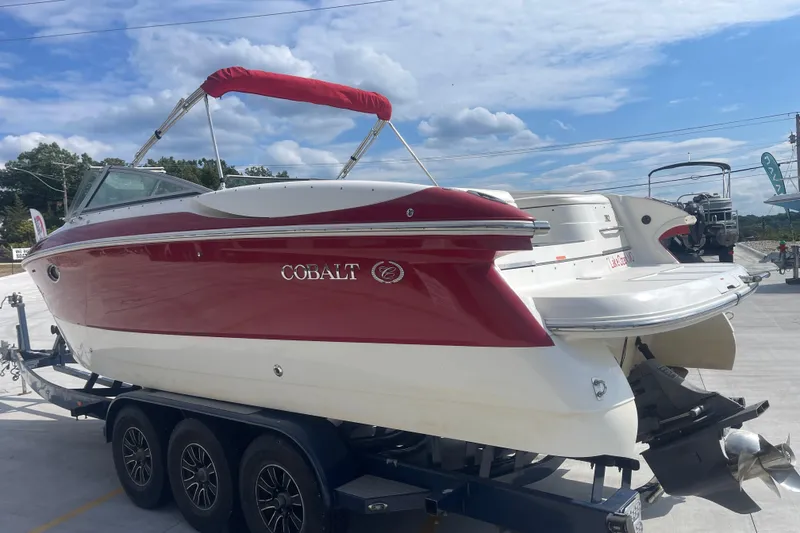 Slide: The Image of 2004 Cobalt 282 boat with red and white exterior on a trailer under a blue sky. - 8