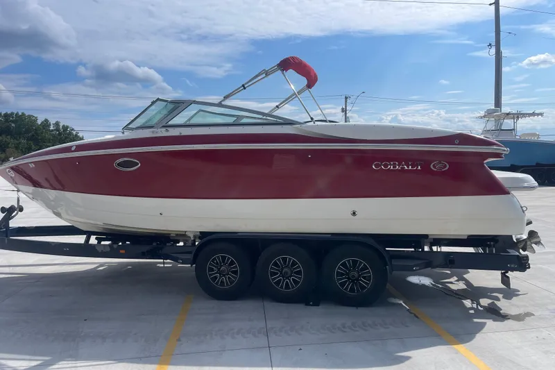 Slide: The Image of 2004 Cobalt 282 boat with red and white exterior on a trailer under a blue sky. - 9