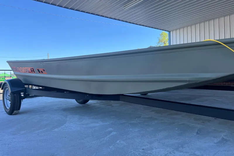The Image of 2026 Tracker Grizzly 12 Jon boat on trailer under a metal roof. - 0