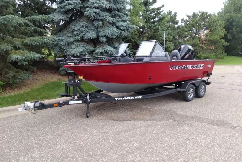Slide: The Image of 2026 Tracker Targa V-19 Combo boat on trailer, parked near trees. - 2