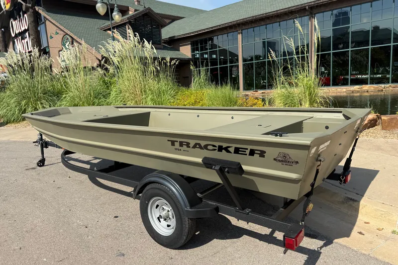 Slide: The Image of 2026 Tracker Grizzly 1754 Utility boat on trailer outside a store, showcasing its rugged design. - 3