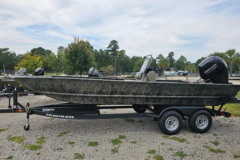 The Image of 2026 Tracker Grizzly 2072 CC boat on trailer, parked outdoors with trees in background. - 1