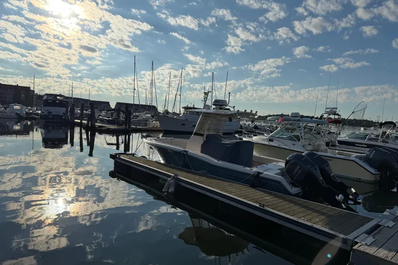 The Image of Boats docked at a marina under a partly cloudy sky, featuring a 2017 Grady White 257 Fisherman. - 1