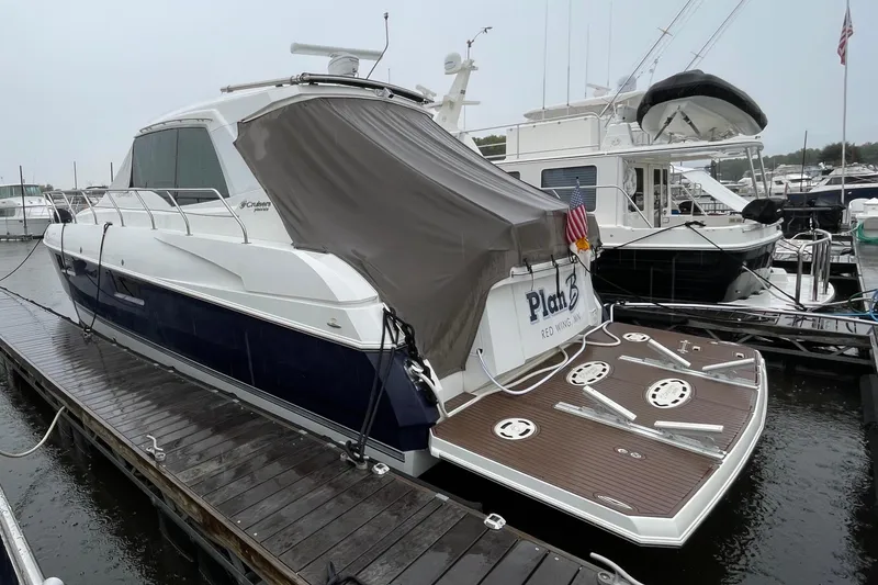 Slide: The Image of 2012 Cruisers Yachts 48 Cantius docked, covered, with wooden deck and American flag. - 12