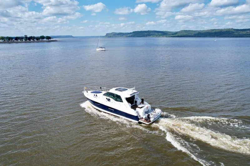 Slide: The Image of 2012 Cruisers Yachts 48 Cantius cruising on a scenic lake under a partly cloudy sky. - 6