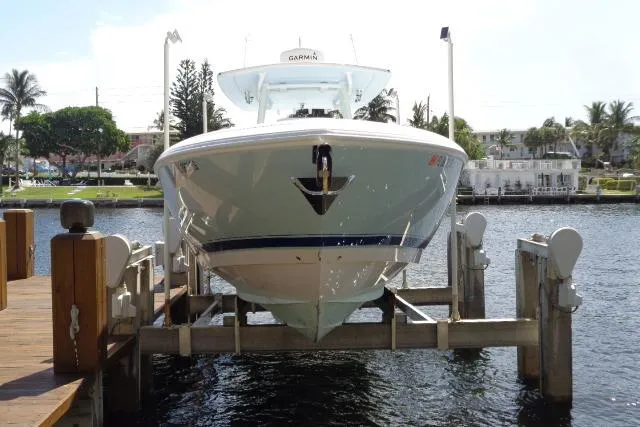 Slide: The Image of 2020 Intrepid 345 Nomad FE boat docked on a lift by the waterfront. - 2