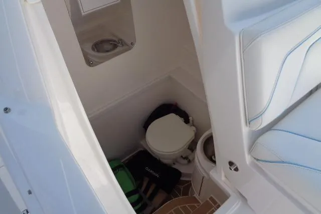 Slide: The Image of 2020 Intrepid 345 Nomad FE boat interior with compact bathroom and seating area. - 20