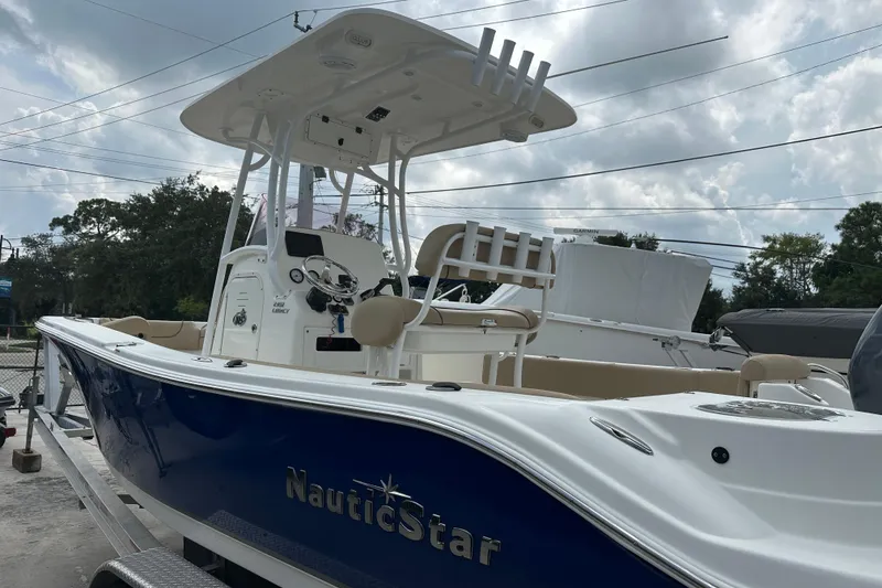 Slide: The Image of 2019 NauticStar 2302 Legacy boat with blue hull, parked outdoors under cloudy sky. - 10