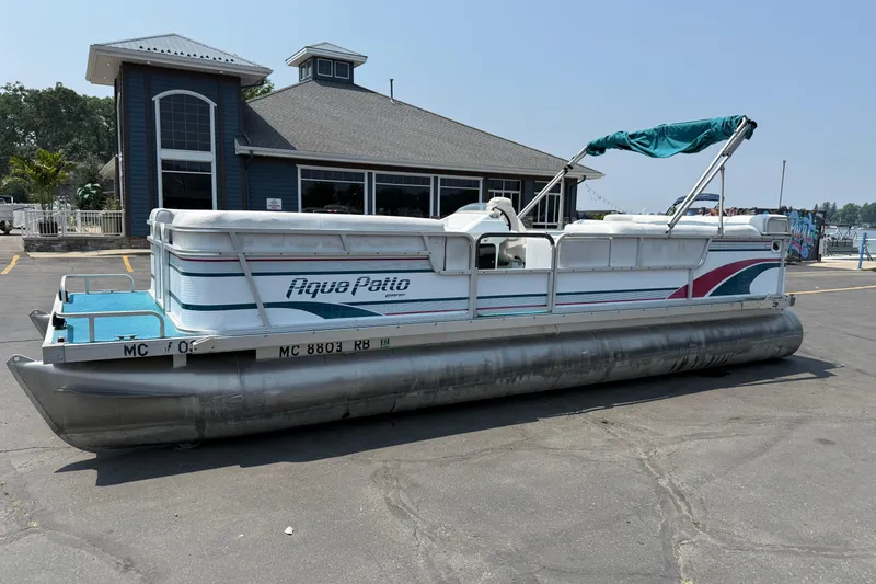 The Image of 1995 AquaPatio 24 pontoon boat parked near a marina building. - 1