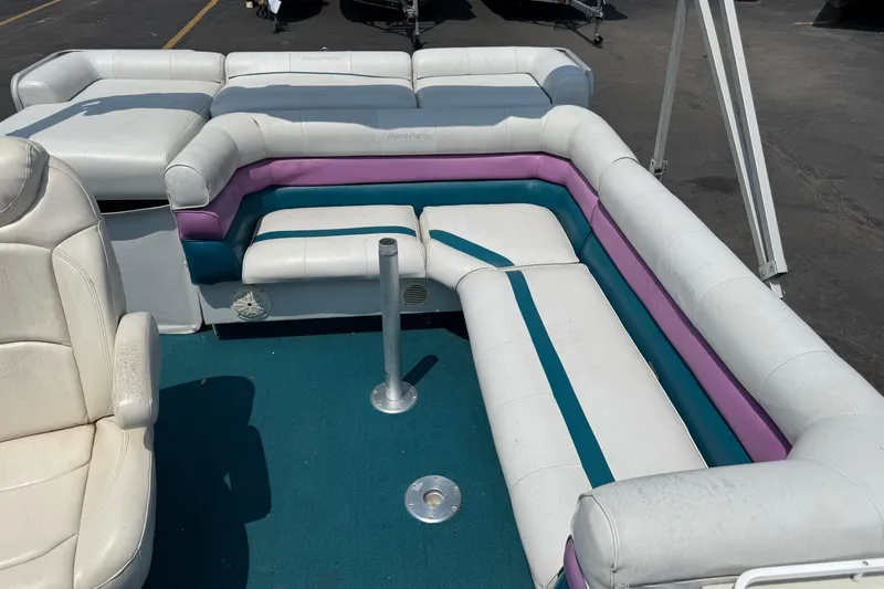 Slide: The Image of 1995 AquaPatio 24 boat interior with white, purple, and teal seating on blue carpet. - 11