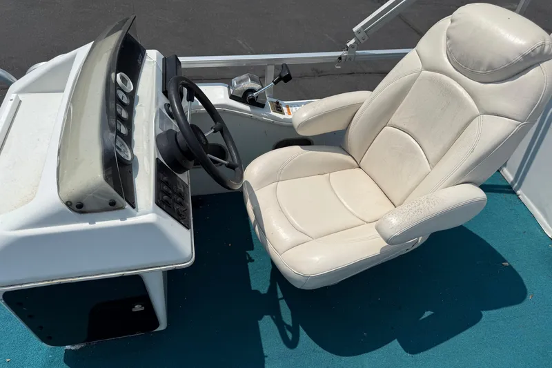 Slide: The Image of Captain's seat and dashboard of a 1995 AquaPatio 24 boat, featuring a steering wheel. - 12