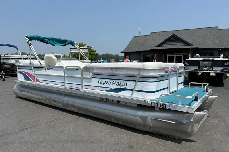Slide: The Image of 1995 AquaPatio 24 pontoon boat with canopy, parked on asphalt near a building. - 3
