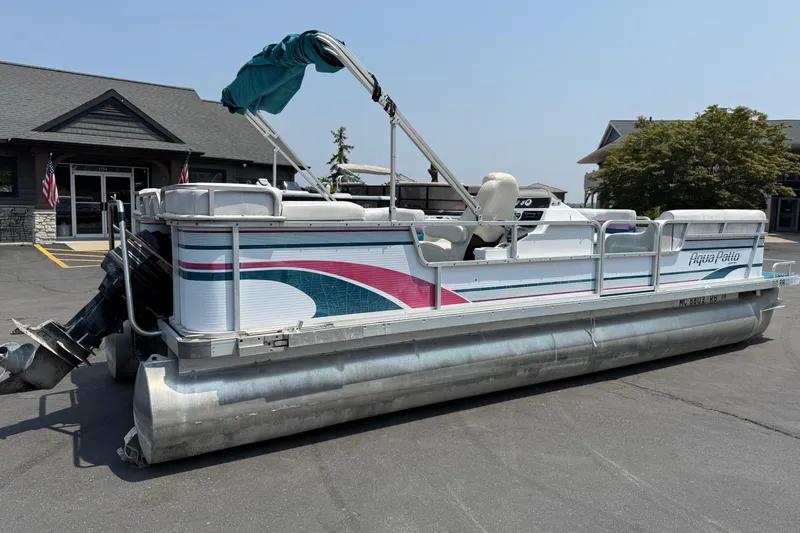 Slide: The Image of 1995 AquaPatio 24 pontoon boat parked outside a building on a sunny day. - 4