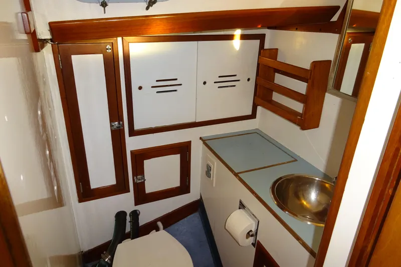 Slide: The Image of 1970 Hinckley Bermuda 40 Custom yacht bathroom with wooden cabinets and stainless steel sink. - 61