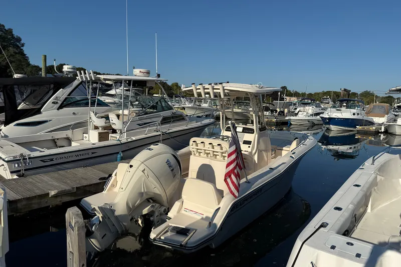 The Image of 2024 Grady-White Fisherman 216 boat docked in a marina, featuring an American flag. - 0
