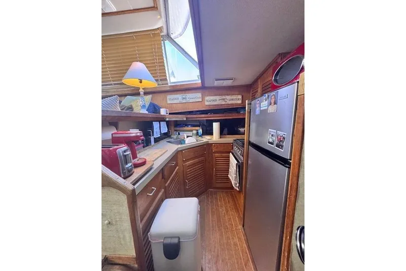 Slide: The Image of 1985 Silverton 40 ACMY yacht kitchen with wooden cabinets, stainless steel fridge, and appliances. - 37