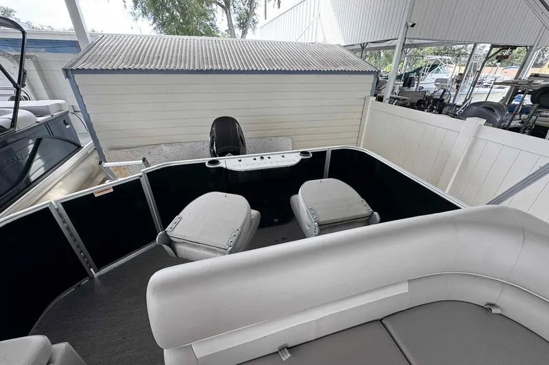 Slide: The Image of 2026 Sweetwater 2086FX boat interior with seating and motor, docked under a shelter. - 7