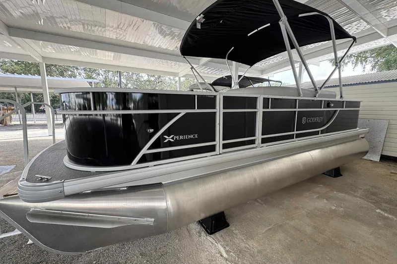 Slide: The Image of 2026 Sweetwater 2086FX pontoon boat with black exterior and canopy, parked under shelter. - 9