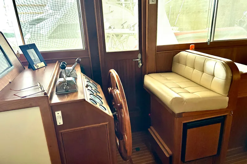 Slide: The Image of Interior helm of 1999 Grand Banks 46 Europa yacht with wooden steering wheel and cushioned seating. - 38