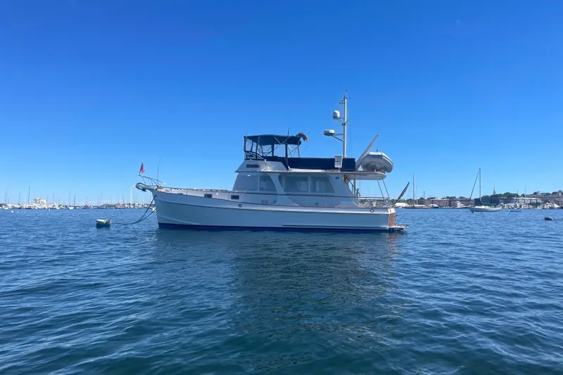 Slide: The Image of 1999 Grand Banks 46 Europa yacht anchored on calm water under clear blue sky. - 52