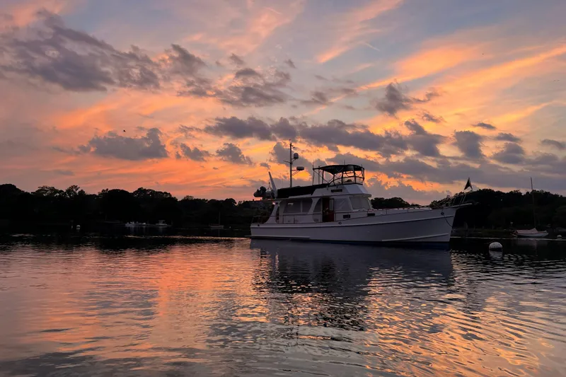 Slide: The Image of Grand Banks 46 Europa yacht at sunset, reflecting on calm water, 1999 model. - 54
