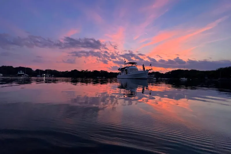 Slide: The Image of Grand Banks 46 Europa yacht at sunset, reflecting on calm water, 1999 model. - 55