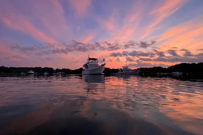 Slide: The Image of Sunset over water with a 1999 Grand Banks 46 Europa yacht reflecting in calm waters. - 56