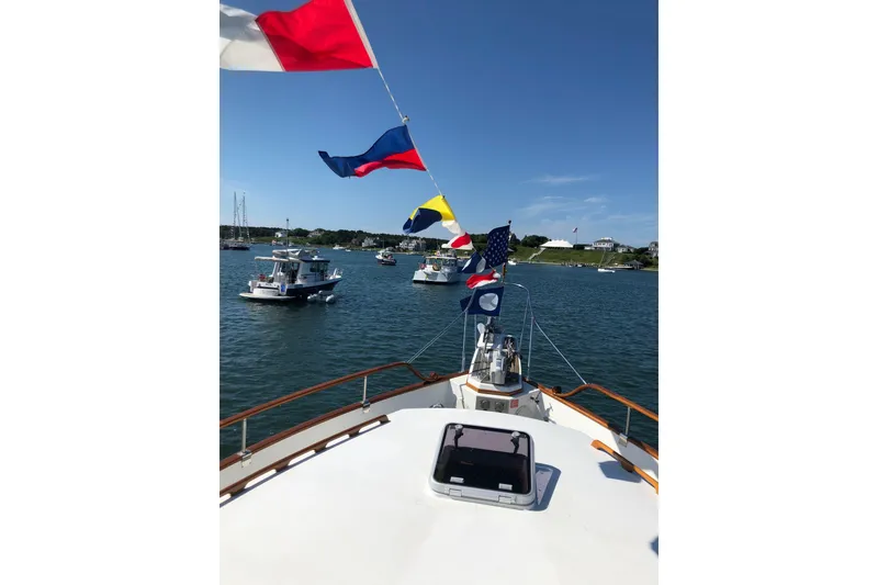 Slide: The Image of Bow view of 1999 Grand Banks 46 Europa yacht with colorful flags on a sunny day. - 58