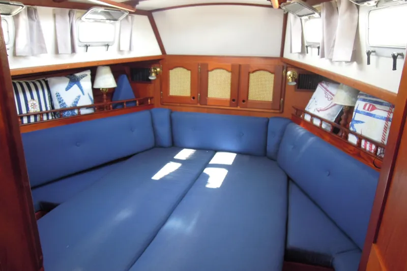 Slide: The Image of Interior of 1990 Gozzard 31 sailboat with blue cushioned seating and wooden accents. - 10