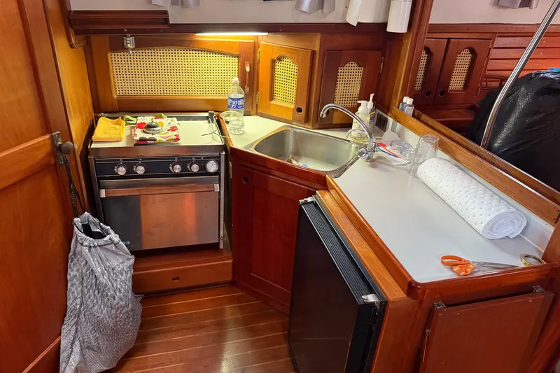 Slide: The Image of Cozy 1990 Gozzard 31 yacht kitchen with stove, sink, and wooden cabinetry. - 12