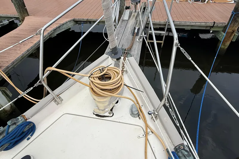 Slide: The Image of Bow of 1990 Gozzard 31 sailboat docked, featuring coiled rope and metal railings. - 17