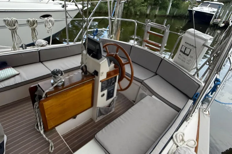 Slide: The Image of Cockpit of 1990 Gozzard 31 sailboat with wooden wheel and cushioned seating. - 2