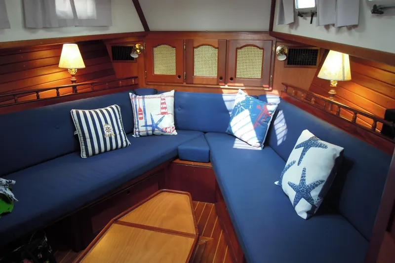 Slide: The Image of Cozy interior of 1990 Gozzard 31 sailboat with blue seating and nautical-themed pillows. - 6