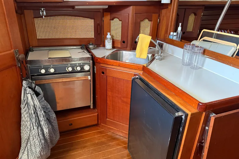 Slide: The Image of Cozy 1990 Gozzard 31 yacht kitchen with stove, sink, and wooden cabinetry. - 7