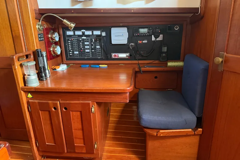 Slide: The Image of Navigation station inside a 1990 Gozzard 31 sailboat with wooden cabinetry and control panels. - 9
