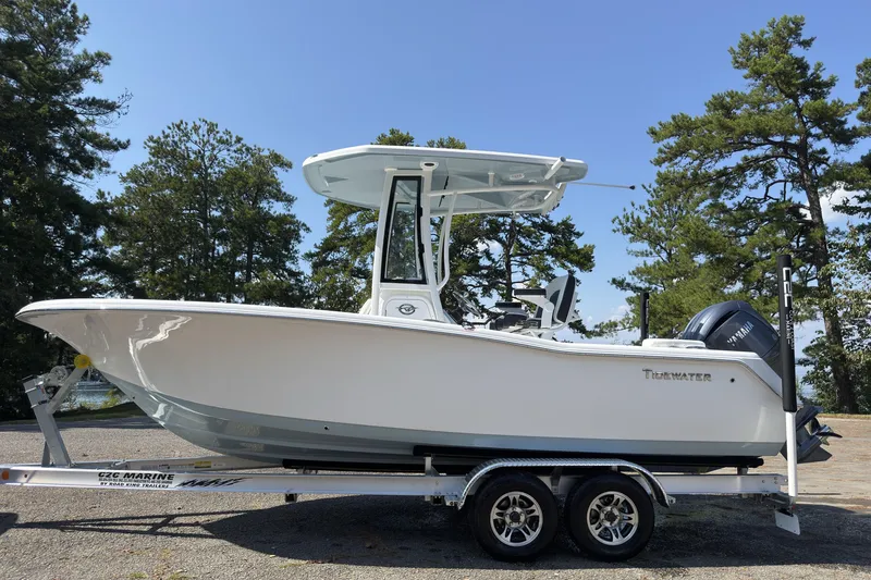 The Image of 2026 Tidewater 220 LXF boat on trailer, surrounded by trees under clear sky. - 0