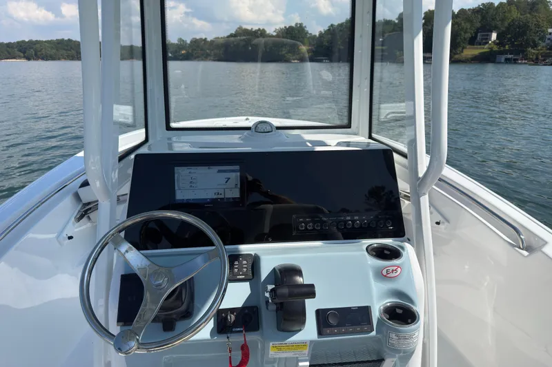 Slide: The Image of 2026 Tidewater 220 LXF boat dashboard with steering wheel and control panel on a lake. - 11