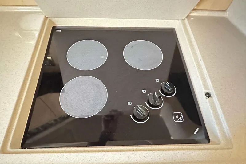 Slide: The Image of Stovetop on 2000 Sea Ray 410 Sundancer yacht, featuring four burners and control knobs. - 24