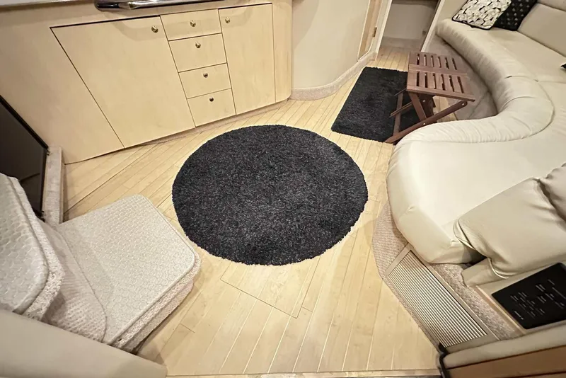 Slide: The Image of Interior of 2000 Sea Ray 410 Sundancer with beige seating, wooden flooring, and black rug. - 33