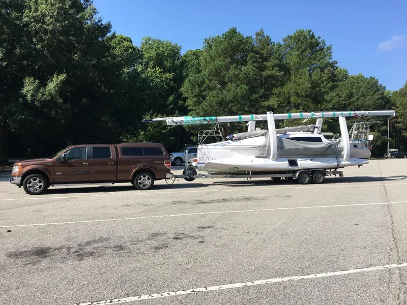 Slide: The Image of Brown truck towing 2017 Corsair Cruze 970 sailboat on trailer in parking lot. - 11