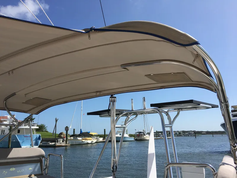 Slide: The Image of 2017 Corsair Cruze 970 #396 sailboat with canopy, docked at a marina under clear blue sky. - 15