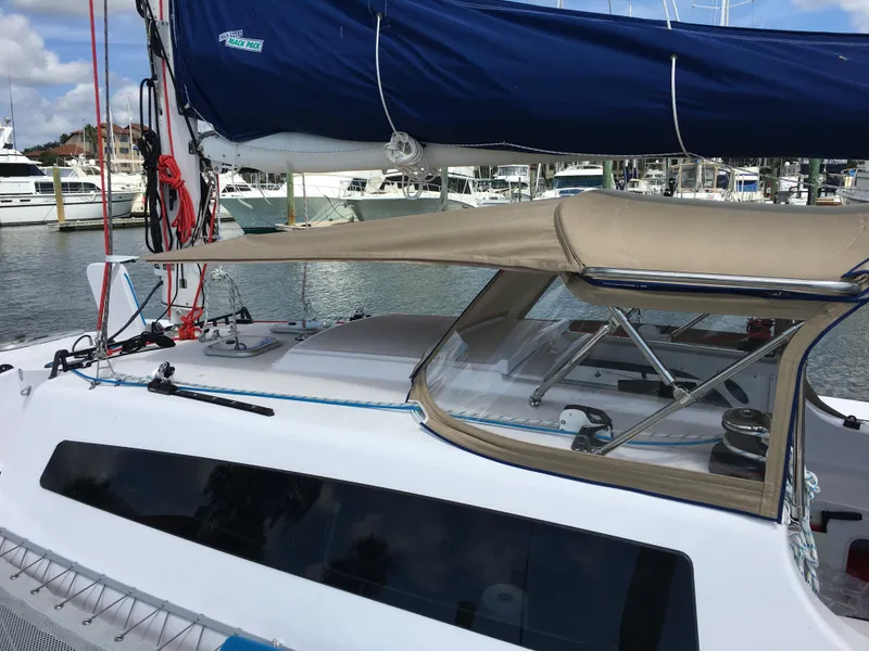 Slide: The Image of 2017 Corsair Cruze 970 sailboat docked, featuring a blue sail and beige canopy. - 18
